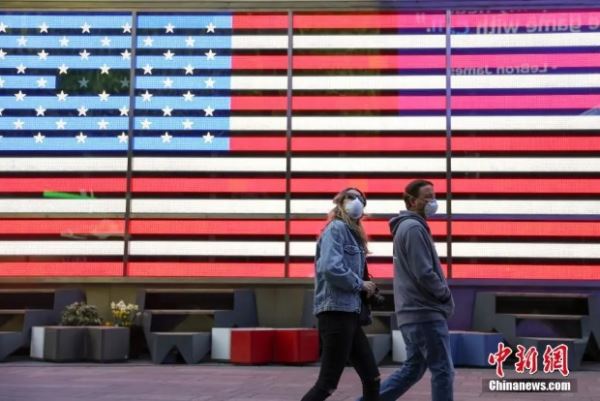 当地时间4月12日，两位戴口罩的市民走过纽约时代广场美国国旗灯箱。(<a target='_blank' href='http://www.chinanews.com/'>中新社</a>记者 廖攀 摄)