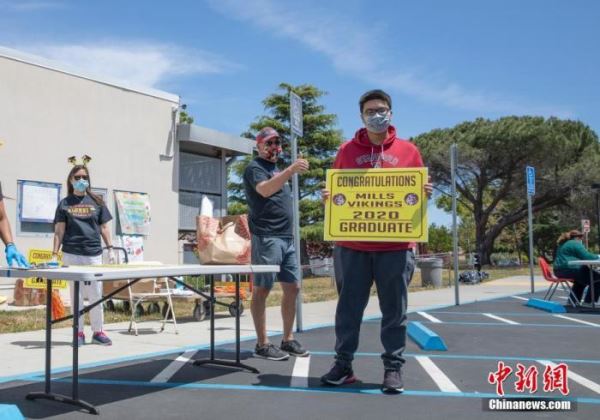 资料图：当地时间5月15日，美国北加州圣马特奥县的米尔斯高中迎来特殊毕业季，毕业生们开车或乘车来到学校工作人员布置的不同站点，完成还书、缴费以及领取毕业物品等环节，学生全程与工作人员没有直接接触。
