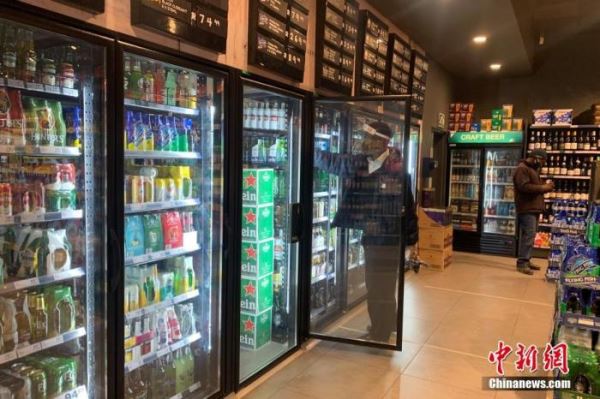 资料图：当地时间7月22日，南非约翰内斯堡，一家酒类商店的店员佩戴面罩整理冰箱内的货物。
<a target='_blank' href='http://www.chinanews.com/'>中新社</a>记者 王曦 摄
