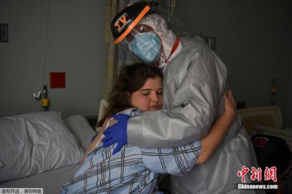 资料图：美国联合纪念医疗中心的首席医疗官与护士克里斯蒂娜·马瑟斯在病房内拥抱。此前，克里斯蒂娜在一次轮班期间报告感觉身体不适，随后检测呈阳性。