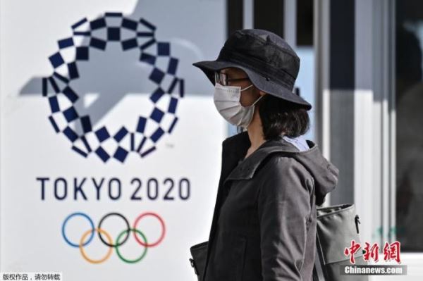 当地时间10月21日，东京奥运会和残奥会组织委员会21日在东京向媒体公开了，观众等进入赛场时通过的行李安检区运营的实证试验。奥组委将根据本次的测试结果等，讨论奥运时的对策。图为一名女士走过2020年东京奥运会海报。