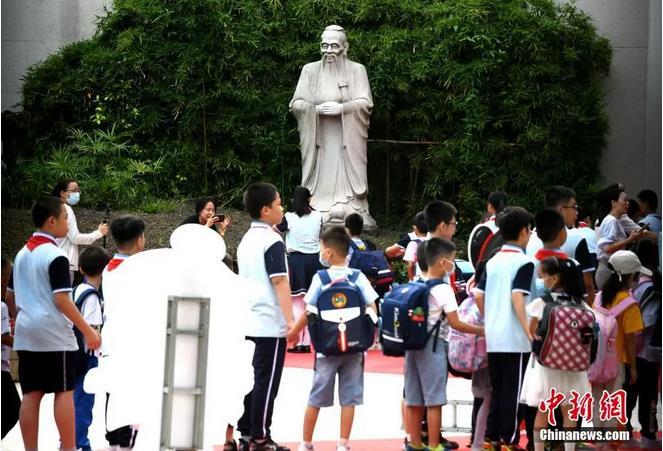 资料图：某小学，学生经过校园里的孔子雕塑并鞠躬。王东明 摄